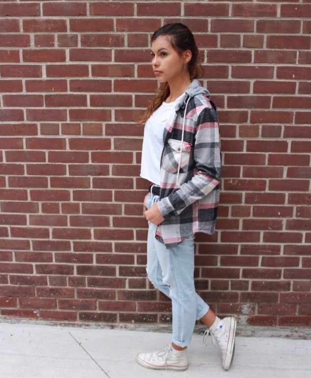Kat , a young fashionable aboriginal womain in Canada, against a red brick wall 