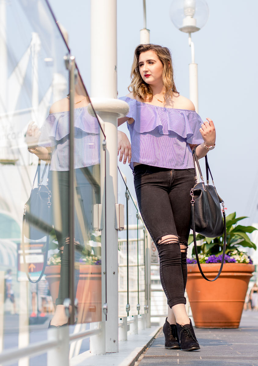 Jessica on Granville St in downtown Vancouver wears ripped jeans and mauve blouse with leather purse
